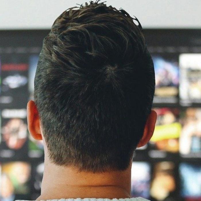 Foto: junger Mann von hinten stehend vor einem Fernsehrbildschirm