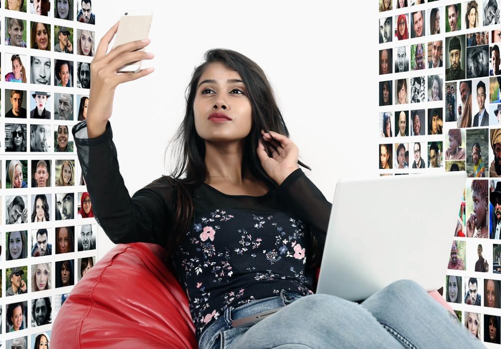 Mädchen sitzend im Sitzsack, welches in ihr Handy schaut, um sie herum sind viele Porträts