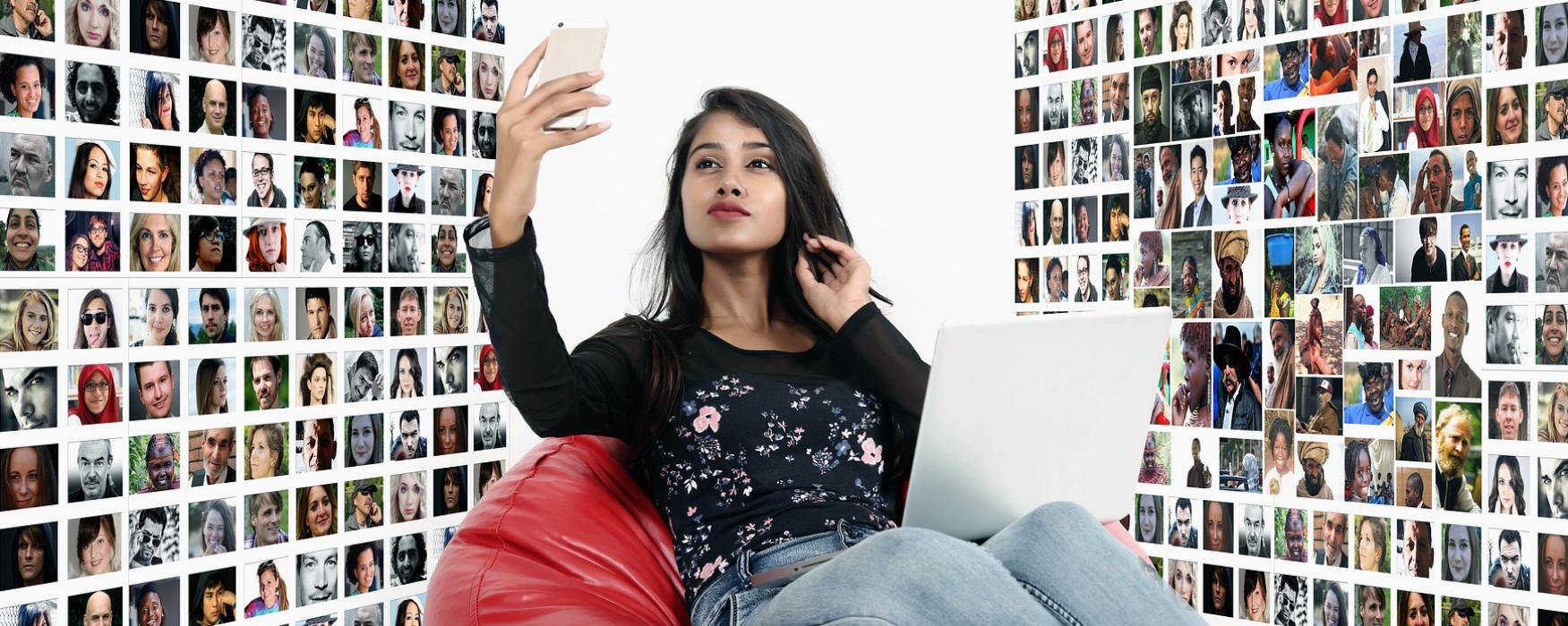 Mädchen sitzend im Sitzsack, welches in ihr Handy schaut, um sie herum sind viele Porträts