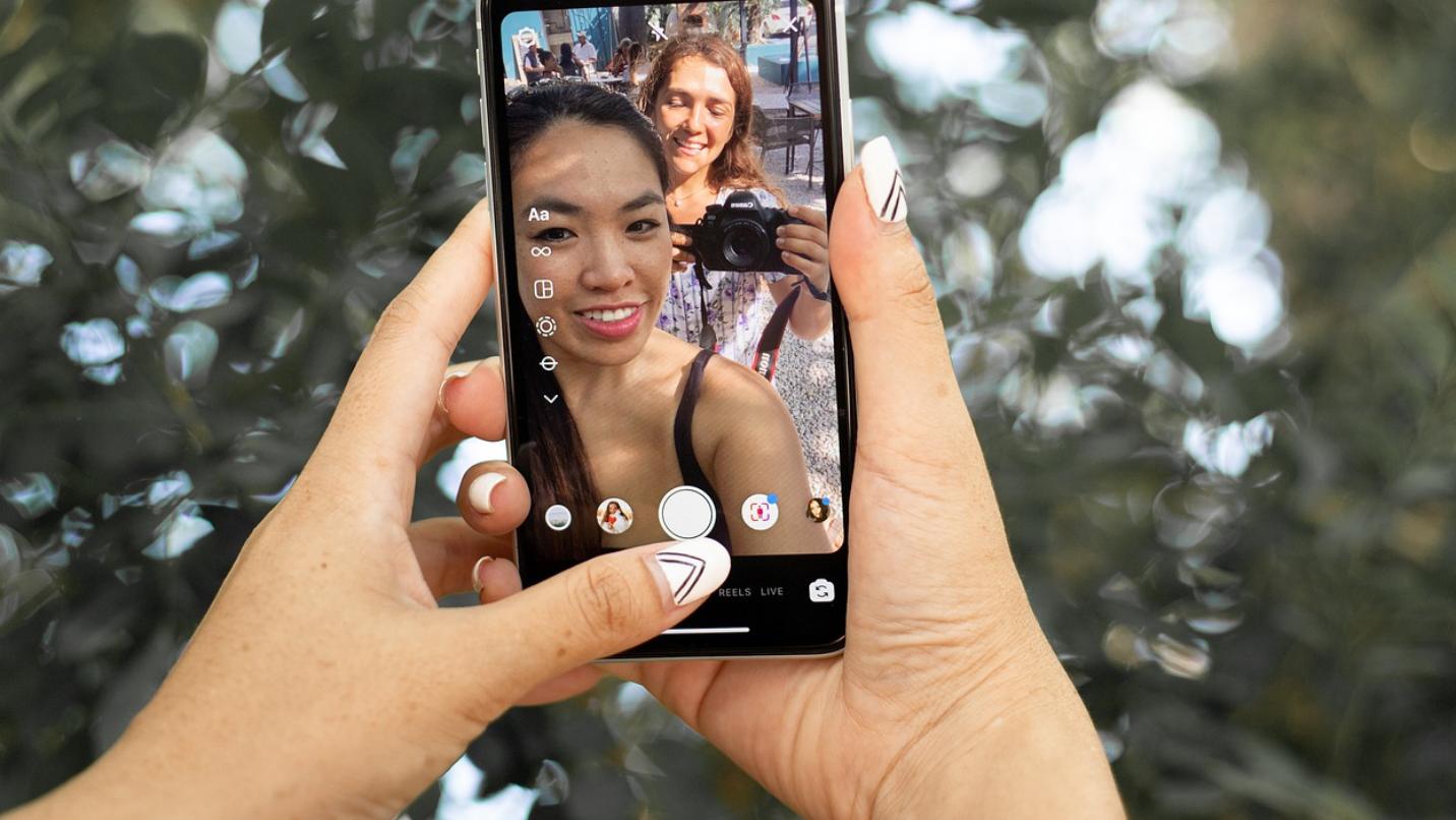 Foto: Frau, die ihr Handy hochhält und gerade einen Livestream am laufen hat bei Instagram